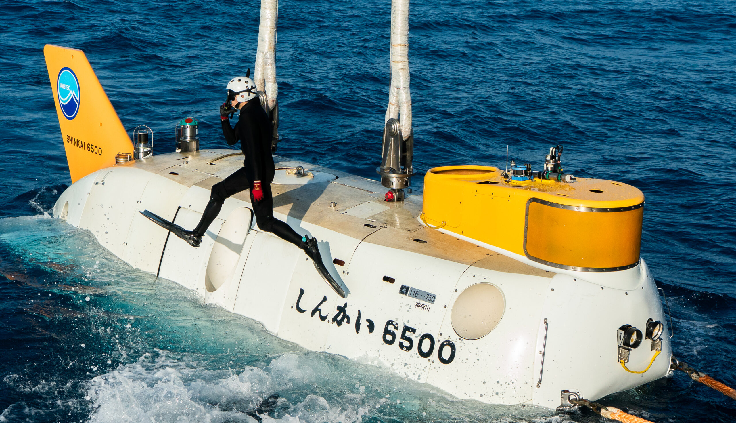 Les plongeurs se remettent à l&rsquo;eau après avoir arrimé le submersible habité de la JAMSTEC, le Shinkai 6500, à la grue qui doit le hisser à bord du RV Yokosuka, à l&rsquo;issue d&rsquo;une plongée effectuée dans le cadre de l&rsquo;expédition Ocean Census 2025 / JAMSTEC Japan. Paul Satchell © The Nippon Foundation-Nekton Ocean Census, JAMSTEC